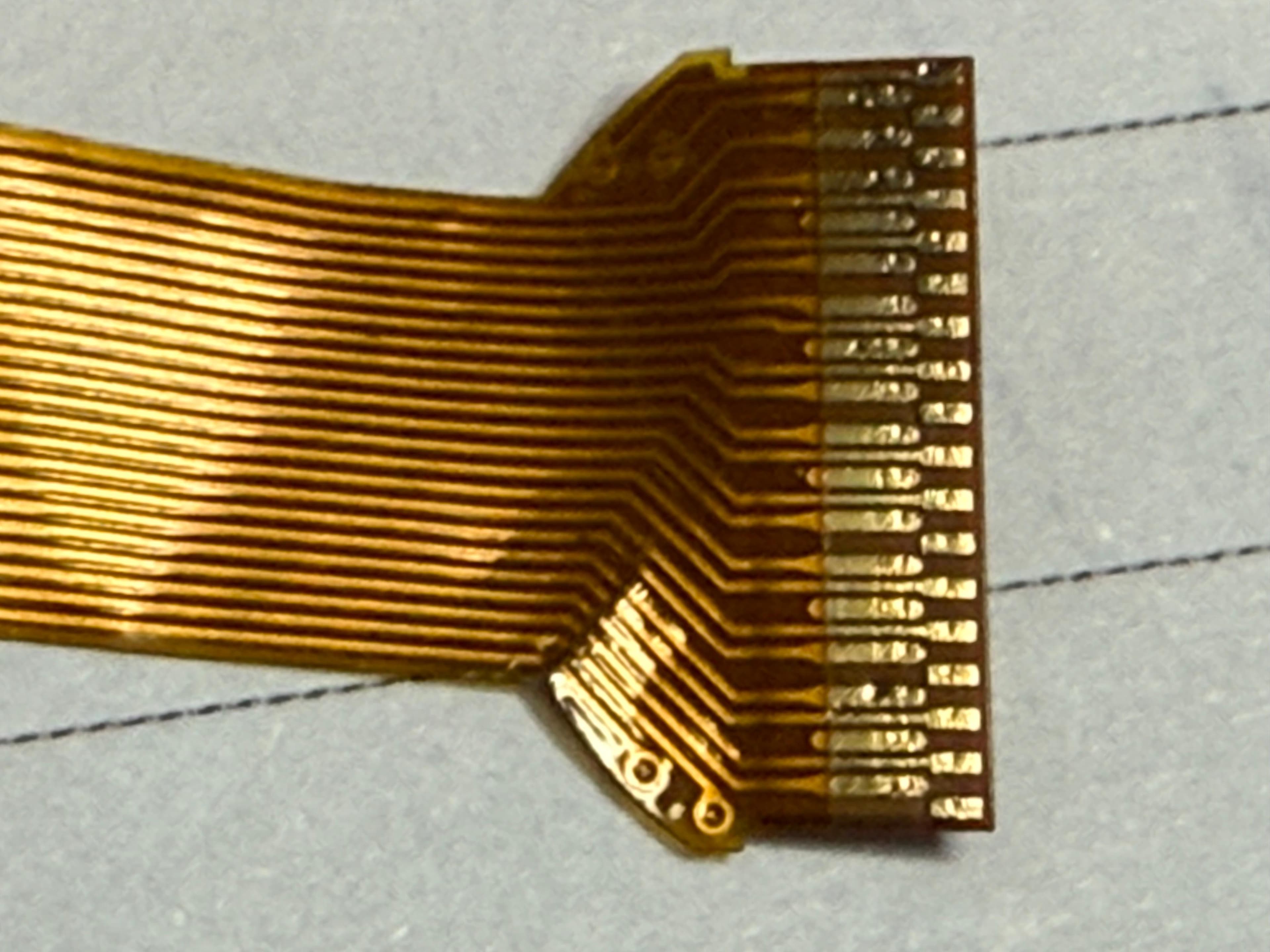 Macro close-up of the fine-pitch gold-plated contact fingers on the flex cable