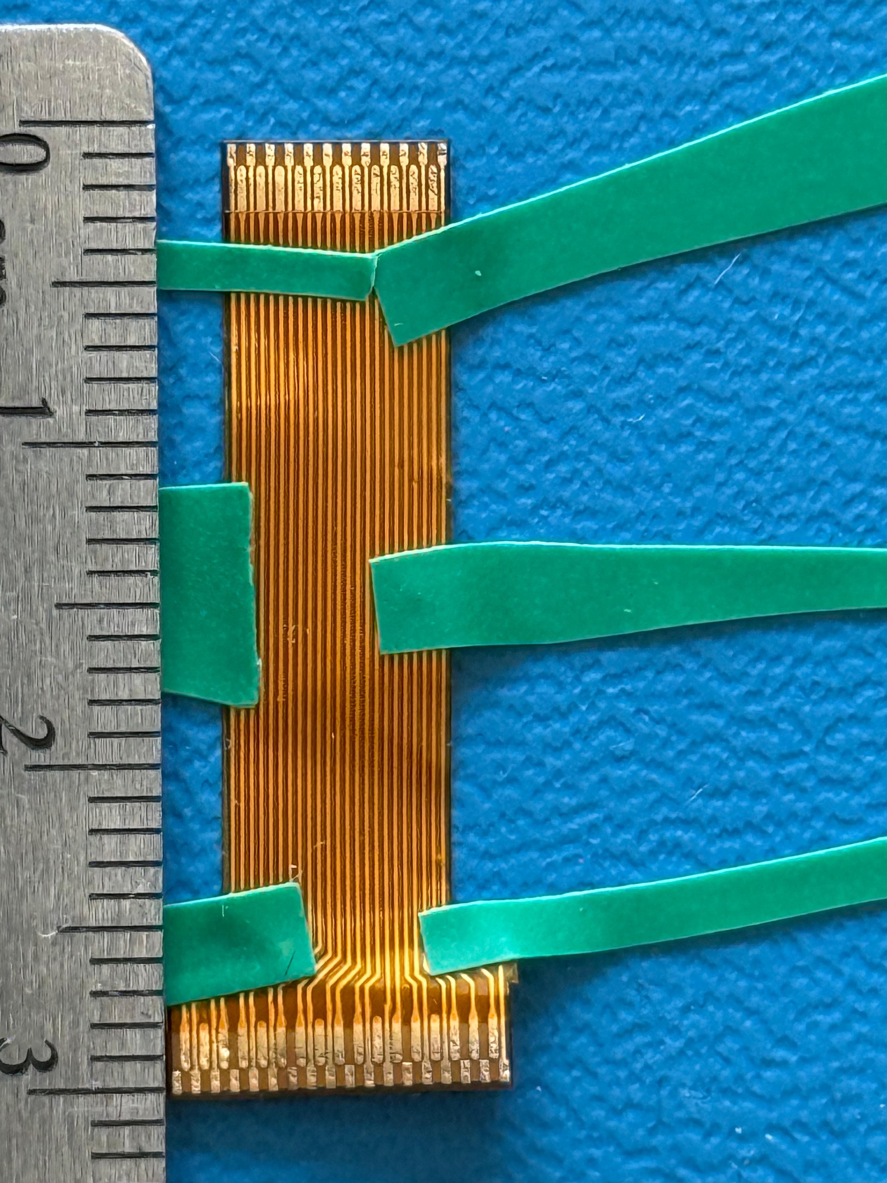 Flexible PCB camera cable next to a ruler for scale